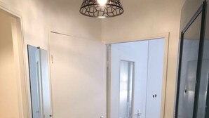 A hallway with wooden flooring, white doors, and a ceiling light fixture.