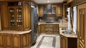 Een keuken met houten kastjes, een roestvrijstalen koelkast, granieten aanrechtbladen en een inbouwoven.