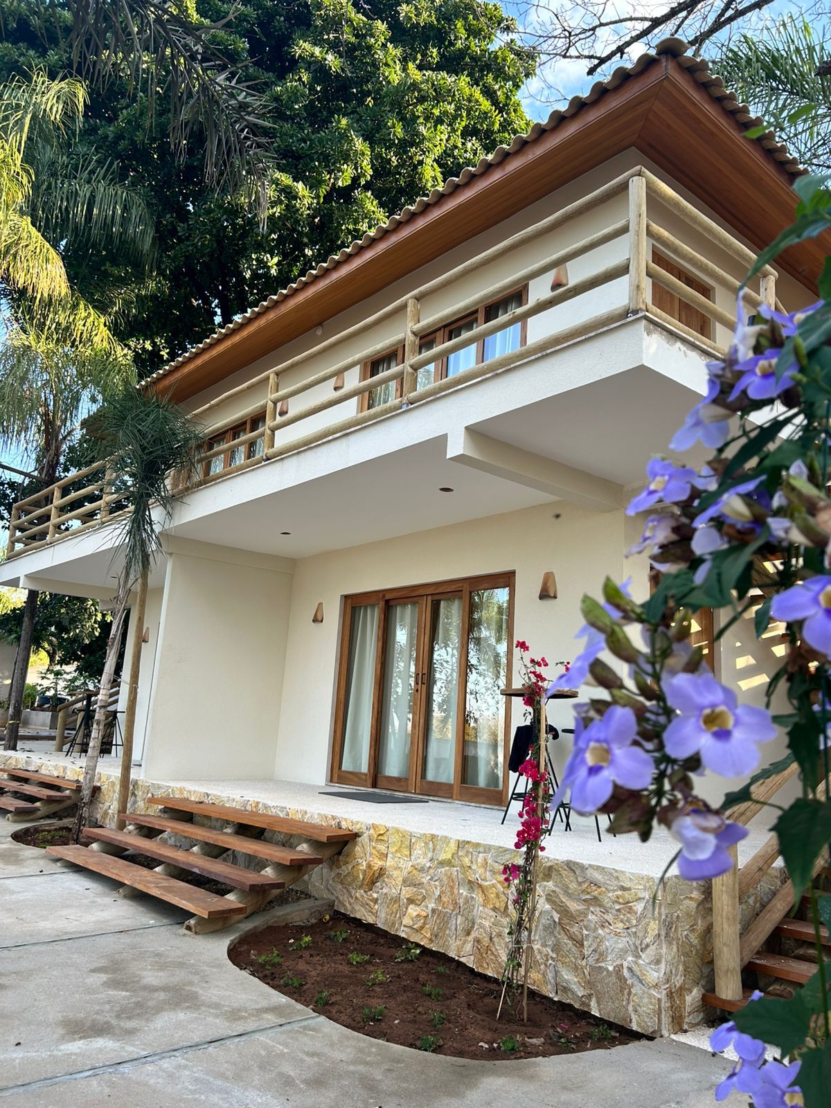 A two-story building with a balcony, a stone base, and a wooden staircase.