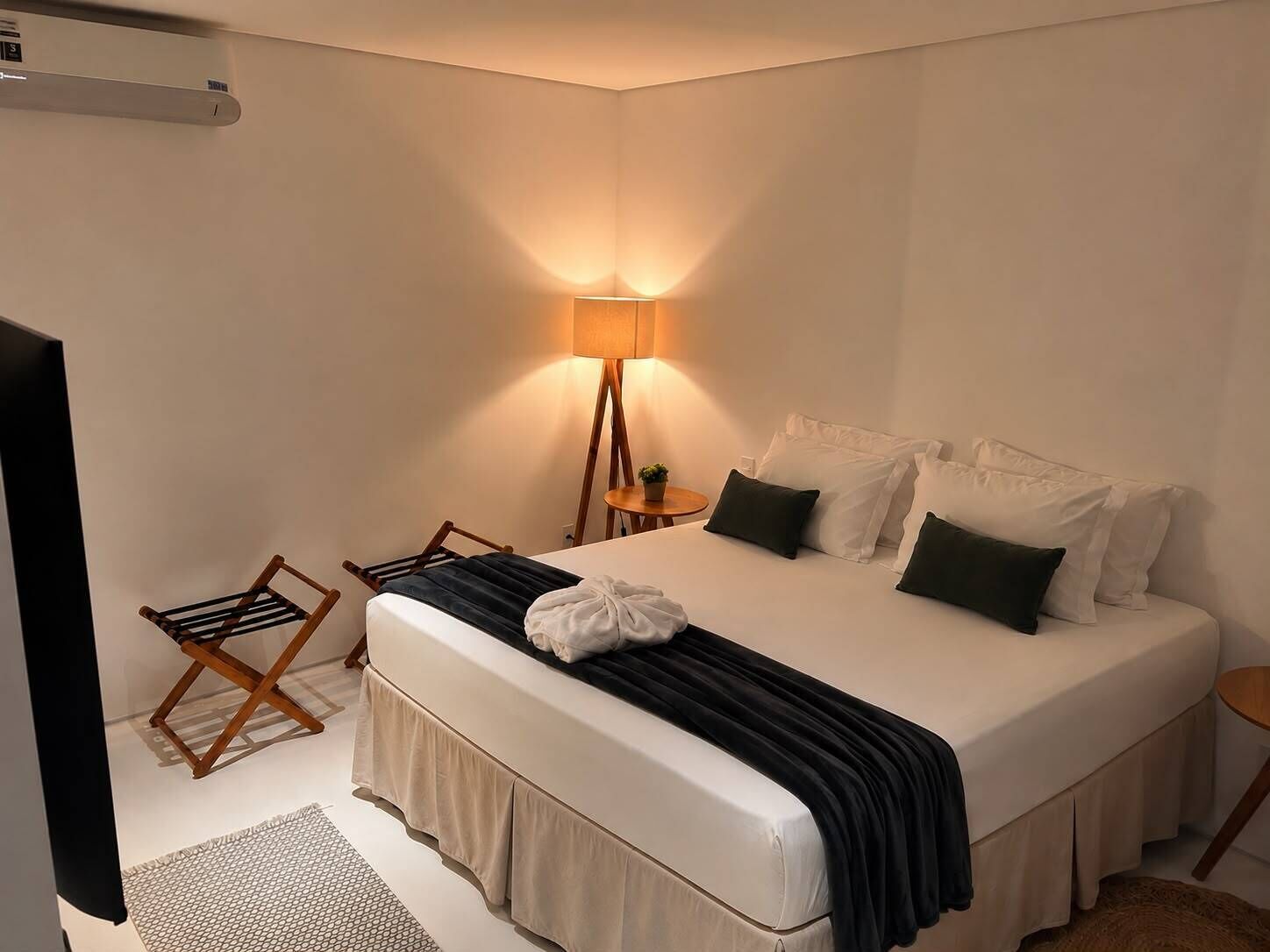 A hotel room with a large bed, a bedside lamp, a small table, and a chair.