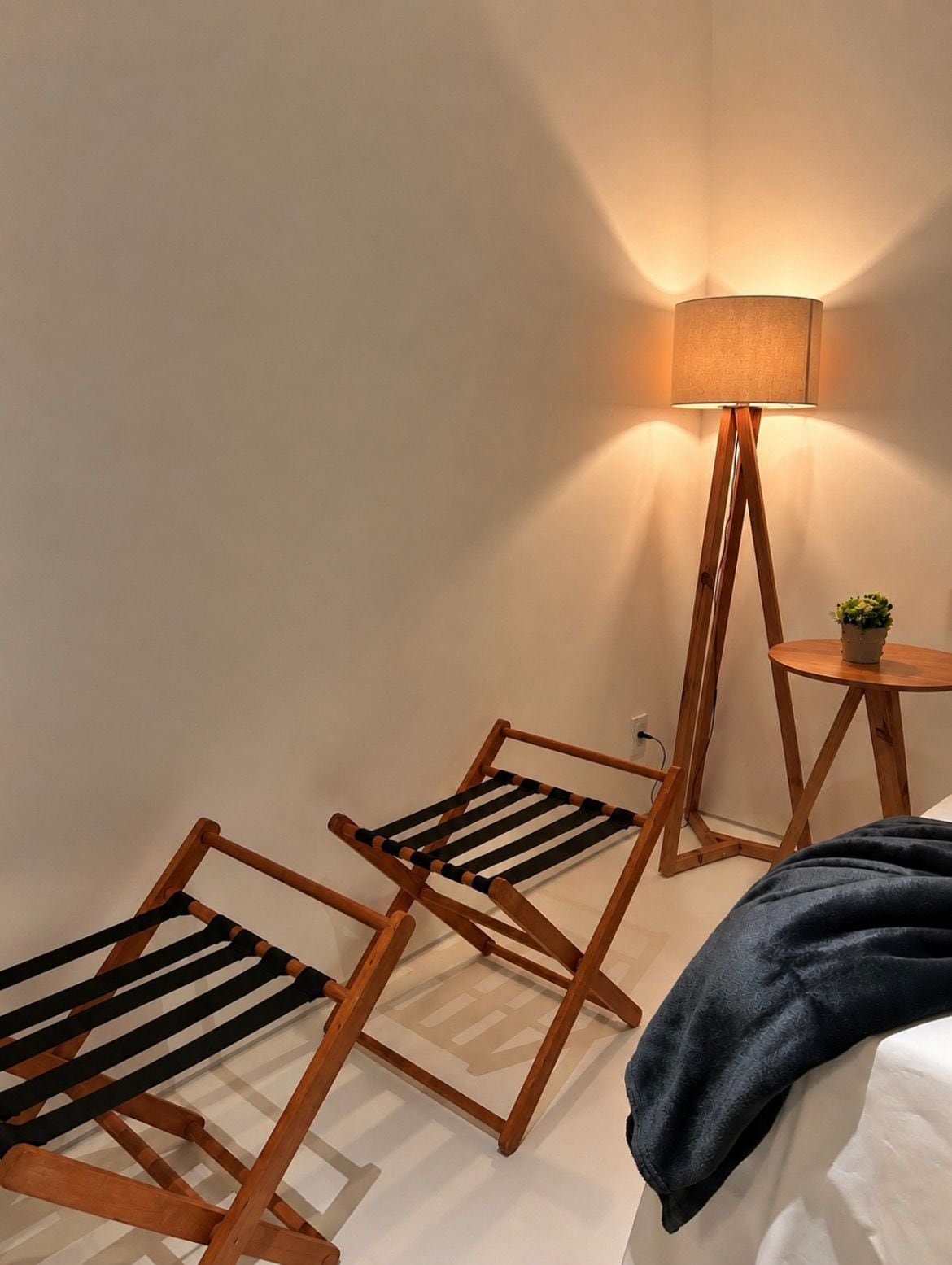 Een kamer met een bed, een staande lamp en twee houten stoelen.