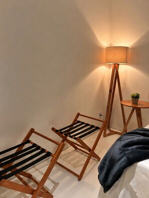 A room with a bed, a standing lamp, and two wooden chairs. - Pousada Manacá Exclusive Suítes  (Rifaina)