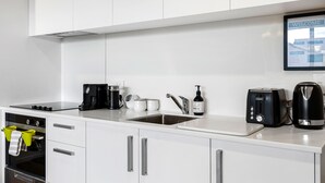 A modern kitchen with white cabinets, a built-in oven, a coffee maker, a toaster, and a kettle.