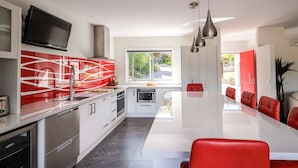 Una cucina moderna con mobili bianchi, un'isola centrale e sedie rosse.
