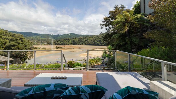 Una terrazza con poltrone relax e un tavolo, con vista su un fiume e colline boscose.