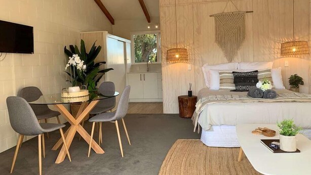 Quarto moderno com uma cama grande, luminárias laterais e vista para o exterior.