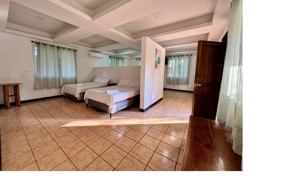 A spacious room with a large bed, a wooden wardrobe, and a tiled floor.