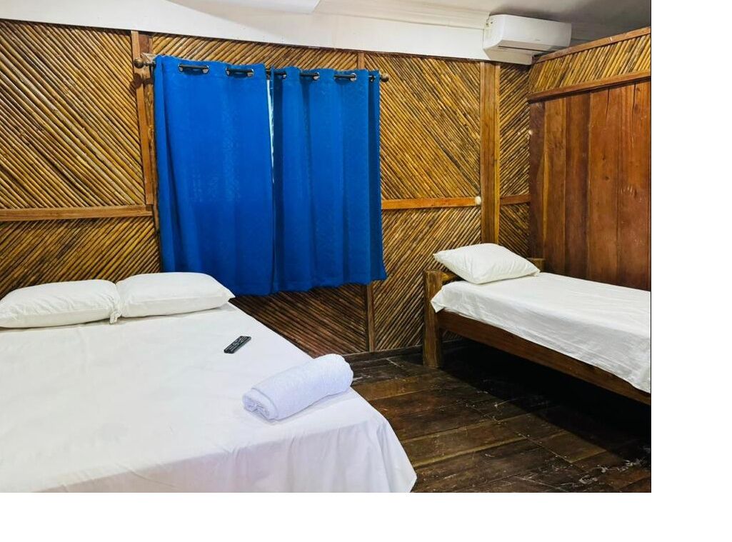 Una habitación con dos camas, una cortina azul y un diseño de pared de madera.