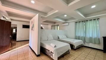 A room with two single beds, a wooden wardrobe, and a tiled floor.