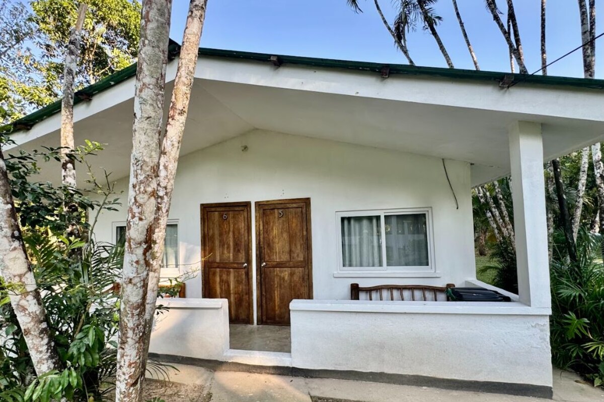 A white building with a covered porch, two wooden doors, and a window.