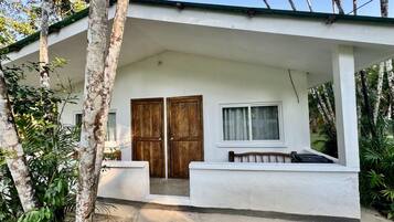 A white building with a covered porch, two wooden doors, and a window.
