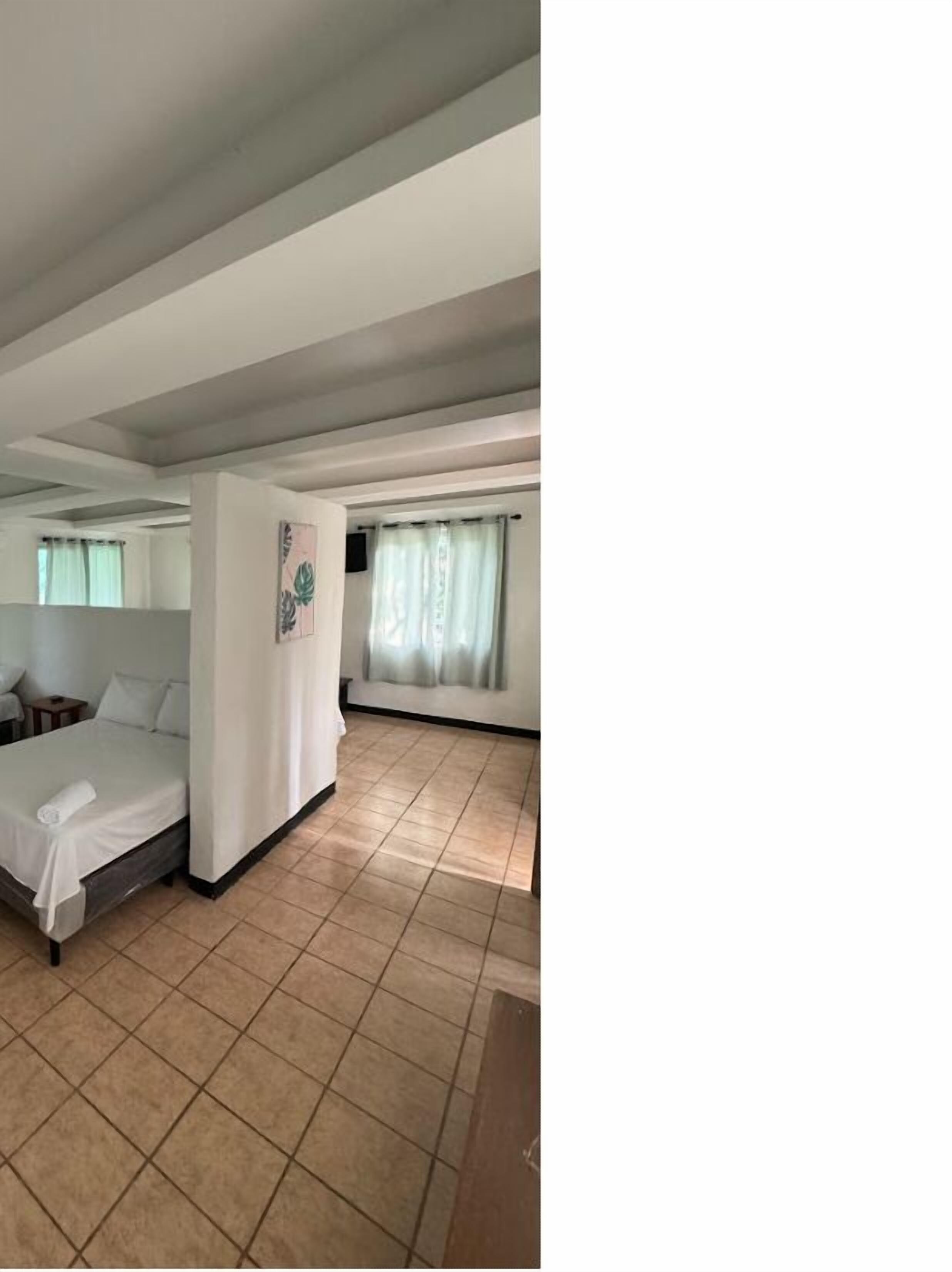 Una habitación de hotel con una cama, una mesita y un ventanal con cortinas.
