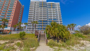 A high-rise hotel with multiple balconies, a central staircase, and a sandy pathway leading to the entrance. - Atlantica Resort 2/2 OF Condo with Dishwasher and Washer/Dryer in Myrtle Beach (Myrtle Beach)