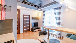 A modern living room with a TV, seating area, and a balcony with a railing.