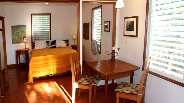 A bedroom with a bed, bedside table, lamp, and a fan. - Stay, relax and explore in Sunrise, our tropical oasis by the Caribbean Sea. (Punta Gorda)