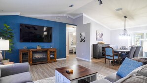Un salon comprenant un téléviseur, un canapé, une table basse et un coin repas avec des chaises et une table.