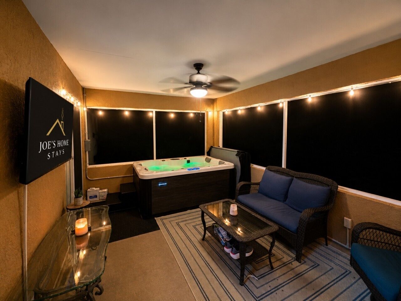 A cozy room with a hot tub, a sofa, a coffee table, and a TV mounted on the wall.