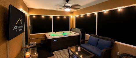 A cozy room with a hot tub, a sofa, a coffee table, and a TV mounted on the wall.