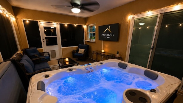Un jacuzzi avec un ventilateur de plafond, un téléviseur fixé au mur et une pancarte sur laquelle on peut lire : « JOE’S HOME STAYS ».