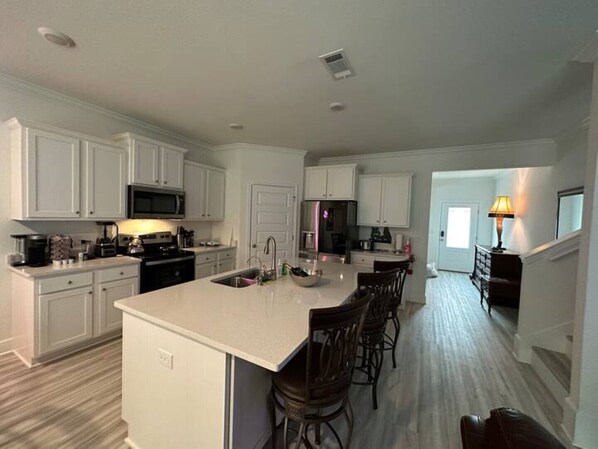 A modern kitchen with white cabinetry, a central island, and a dining area with bar stools.