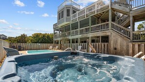 Un bain à remous avec une terrasse en bois et un bâtiment à plusieurs niveaux en arrière-plan.