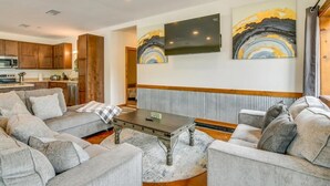 Una sala de estar con un sofá gris, una mesa de centro y obras de arte en la pared.