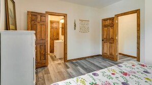 Una habitación con puertas de madera, un refrigerador blanco y una cama con colcha estampada.