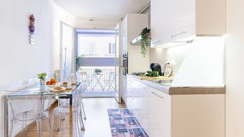 Una cucina moderna con un tavolo da pranzo in vetro e sedie, una pianta pensile e vista all'esterno.