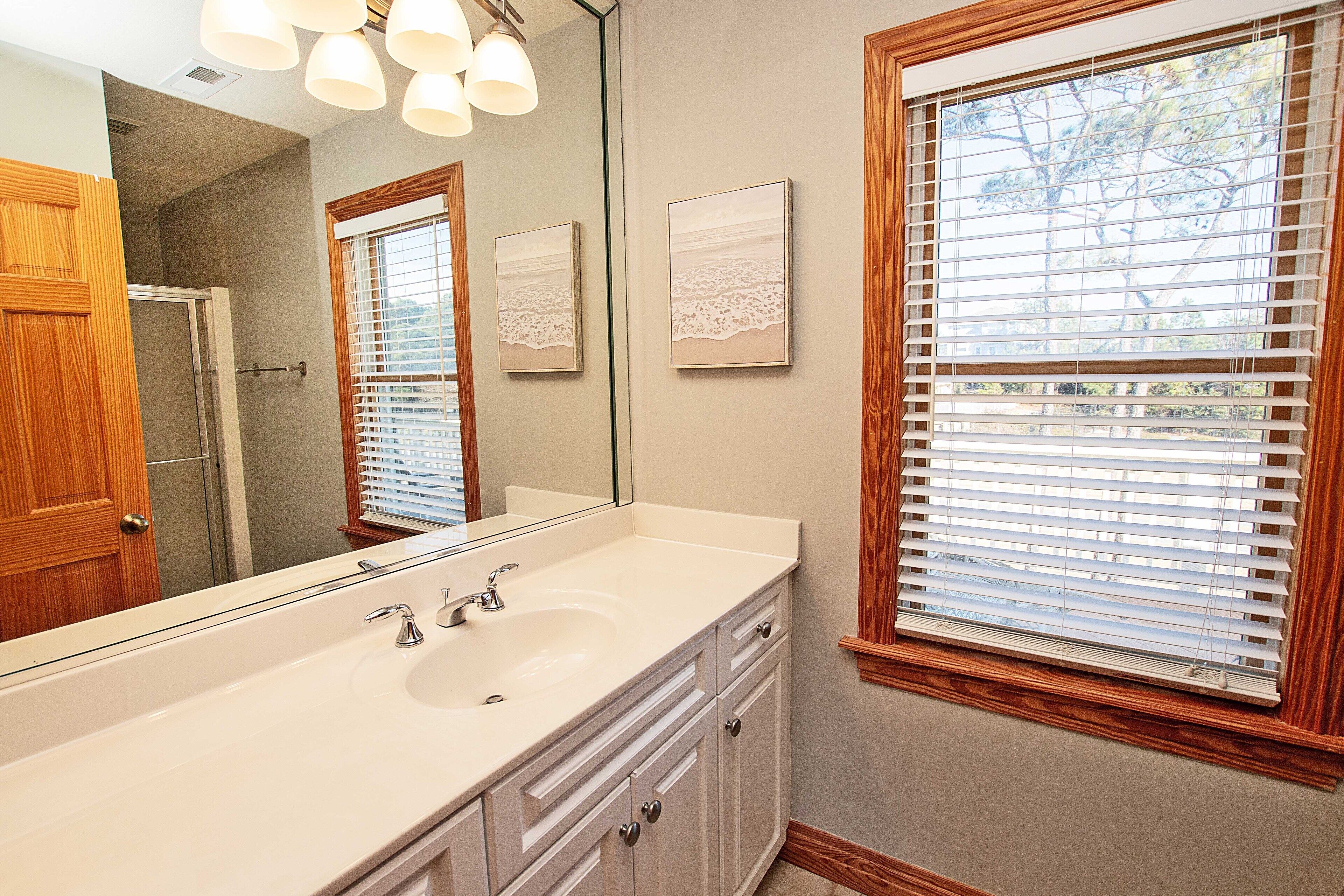 A bathroom with a large mirror, a sink, and wooden cabinetry.