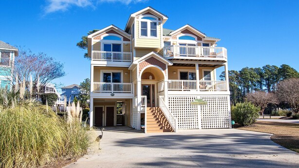 A two-story house with a balcony on the second floor, a front porch, and a staircase leading to the entrance.
