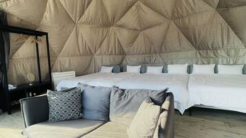Een ruime slaapkamer met een groot bed, een sofa en een uniek geometrisch plafondontwerp.