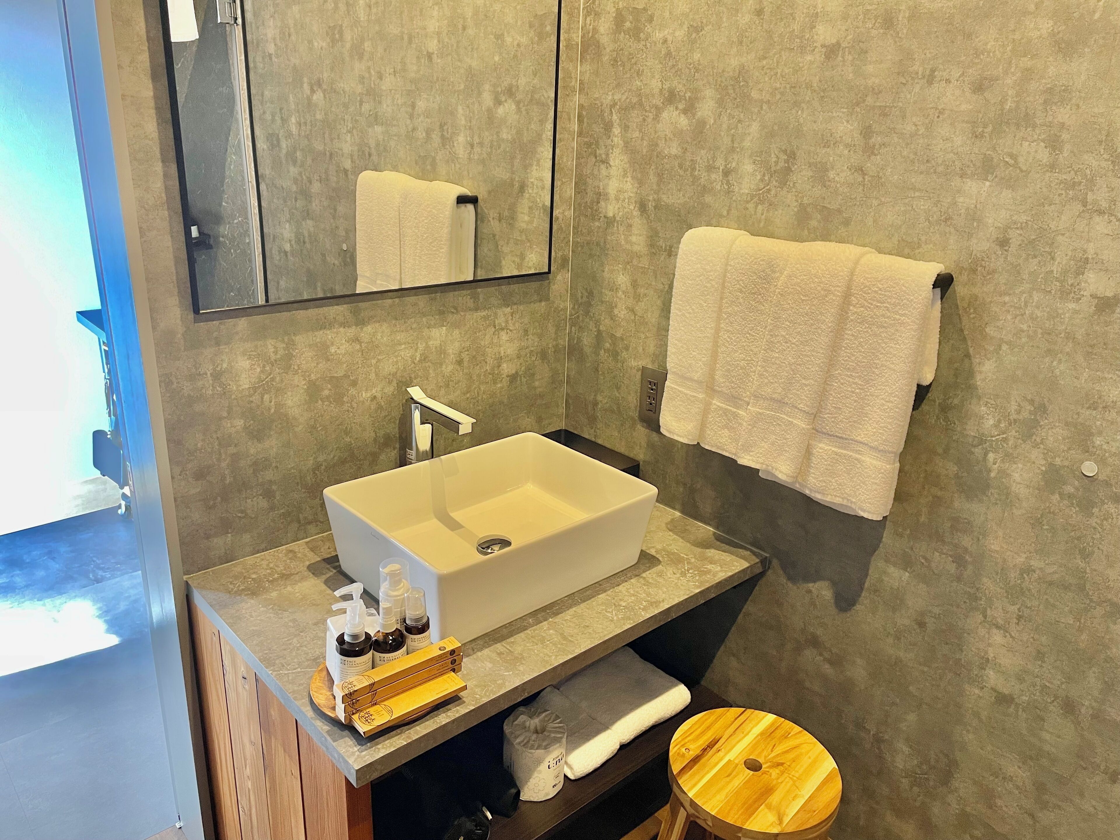 A bathroom with a white sink, mirror, and towel rack.
