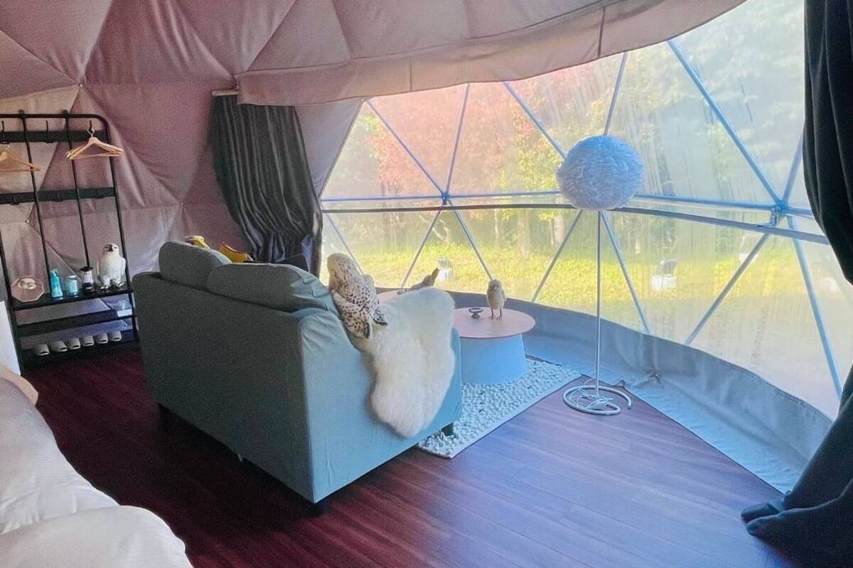 Um quarto acolhedor no estilo de tenda, com sofá, uma mesinha e luminária pendente.
