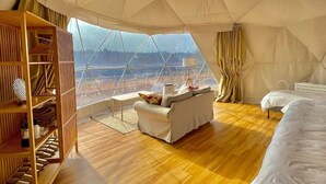 Amplia habitación con toldo, piso de madera, un sofá, una cama y un armario.