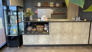 Un área de recepción con un expositor de vidrio que contiene bebidas, una laptop y un letrero que dice 'Redondo'.