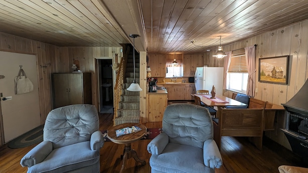 L’intérieur d’une cabane comprend deux fauteuils, une table à manger, un coin cuisine et une cheminée.