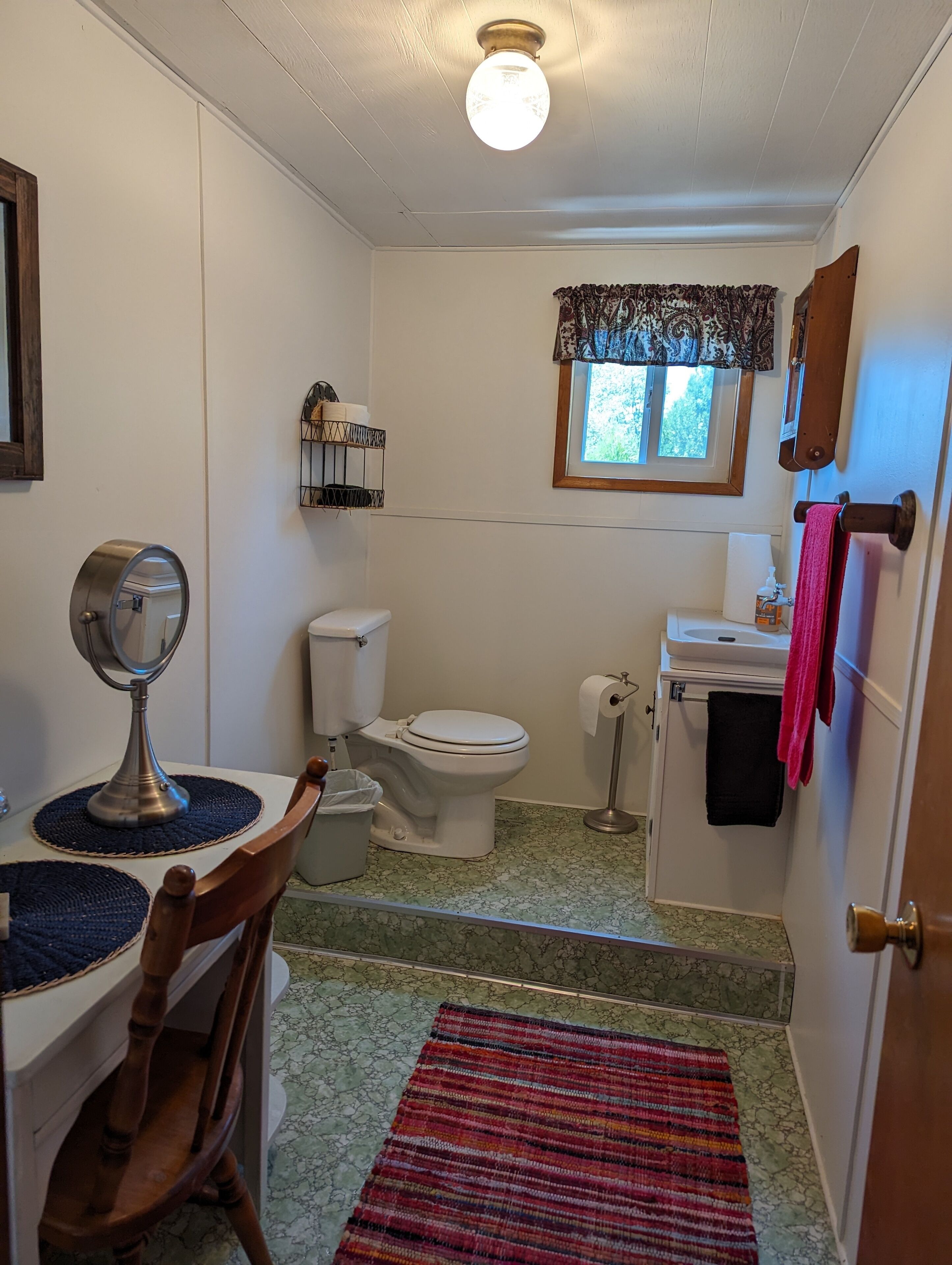 Een kleine badkamer met toilet, wastafel en spiegel.