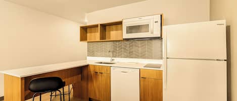 Una cocina compacta con microondas, refrigerador y lavavajillas.