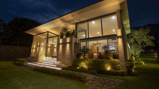 A modern house with a large glass facade, stone pillars, and a well-lit entrance. - Casa del Valle, cozy and with a beautiful view.  (Tepoztlán)