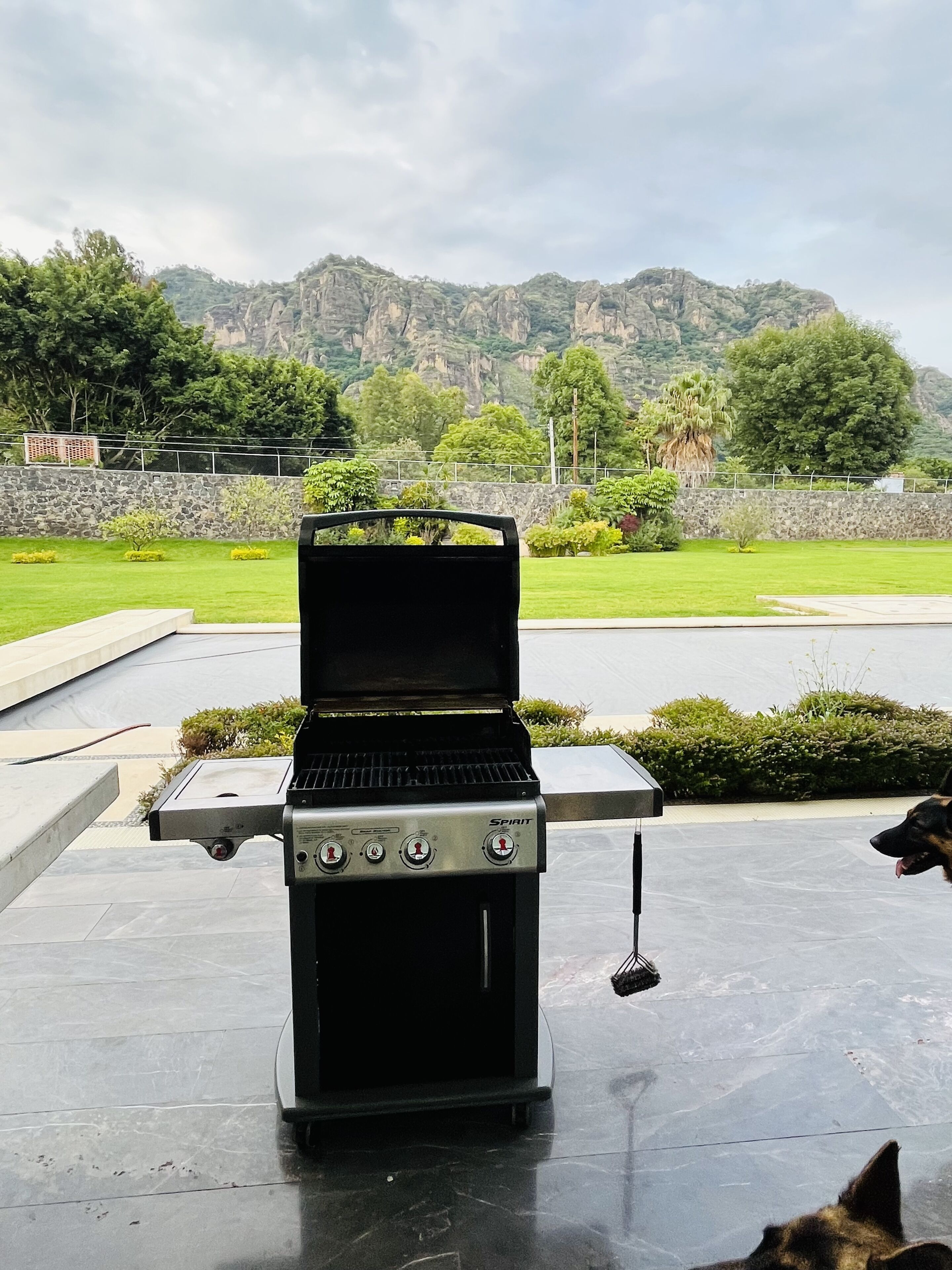 Ein Grill mit Blick auf Berge und eine Steinmauer im Hintergrund.