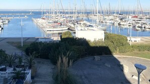 En lystbådehavn med mange både i havnen, en klar himmel og en sti ned til vandet.