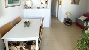 Et moderne køkken med hvide skabe, et spisebord med en stol med ko-print, og en hængende lampe.