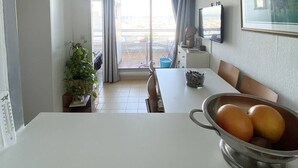 Et moderne køkken med spiseplads, en potteplante og udsigt gennem glasdøren.