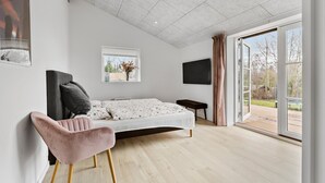 A modern bedroom with a bed, a TV, a window, and a view of the outdoors. - Gorgeous home in Melby with WiFi (Melby)