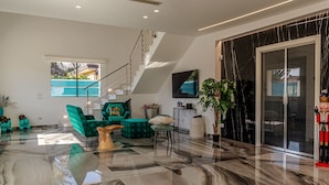 A spacious living area with a high ceiling, a staircase, and a large window. - Elegant villa with pool in Mascali (Mascali)