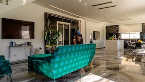 A spacious living area with a teal sofa, a dining area with a table and chairs, and a kitchen in the background. - Elegant villa with pool in Mascali (Mascali)
