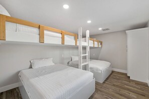 A bedroom with two beds, wooden headboards, a ladder, and a wardrobe.