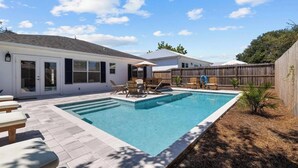 Un patio trasero con piscina, mobiliario de jardín y valla de madera.