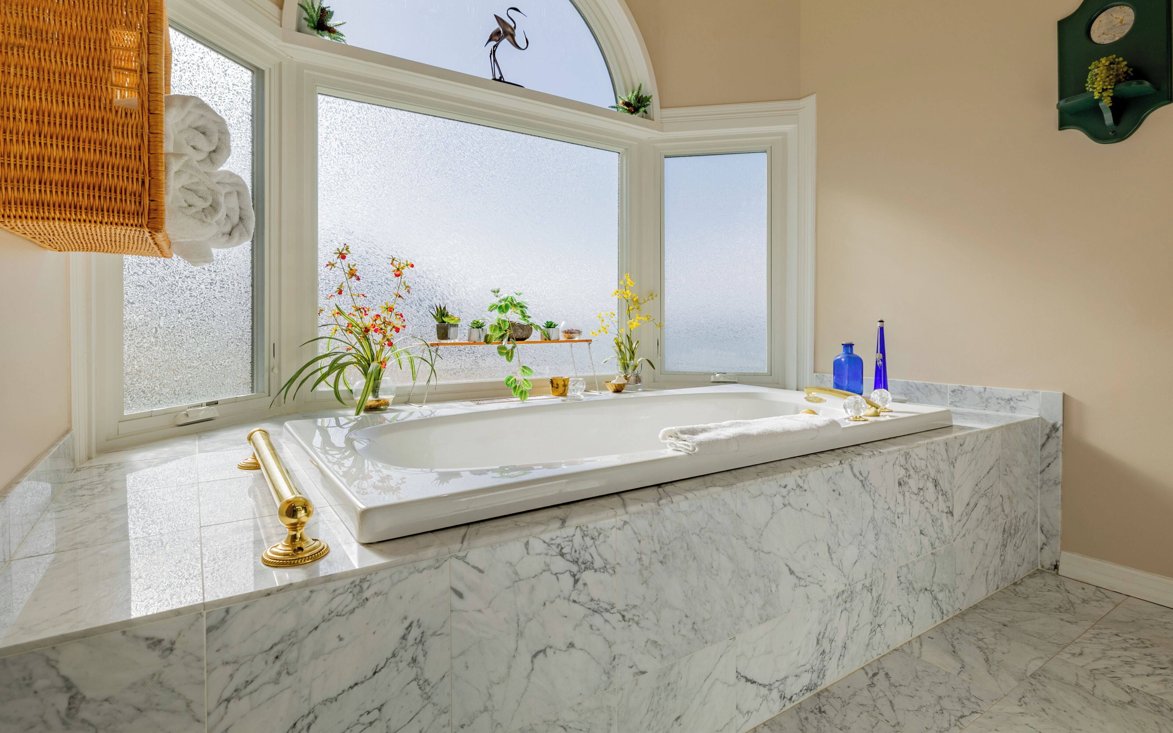 Ein Badezimmer mit einer großen Badewanne, einem Fenster mit Ausblick und einem Regal mit Pflanzen.