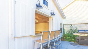 An outdoor seating area with metal chairs and a table, a grill, and a wooden deck.
